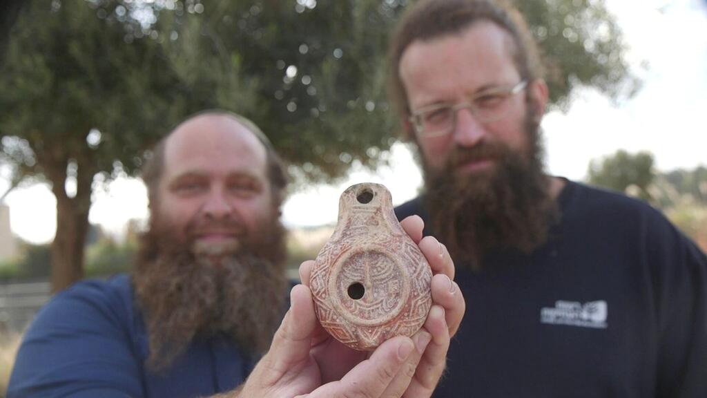 מיכאל טשרנין ובנימין סטורצ'ן מחזיקים את הנר הנדיר (צילום: אמיל אלג'ם, רשות העתיקות) מיכאל טשרנין ובנימין סטורצ'ן מחזיקים את הנר הנדיר