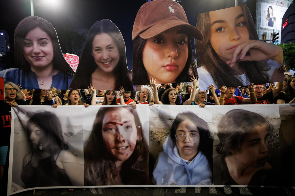 פניהן של ארבע התצפיתניות החטופות - אגם ברגר, לירי אלבג, נעמה לוי וקרינה ארייב - לפני ואחרי החטיפה, על גבי כרזות בהפגנה הקוראת לשחרור החטופים, שער בגין