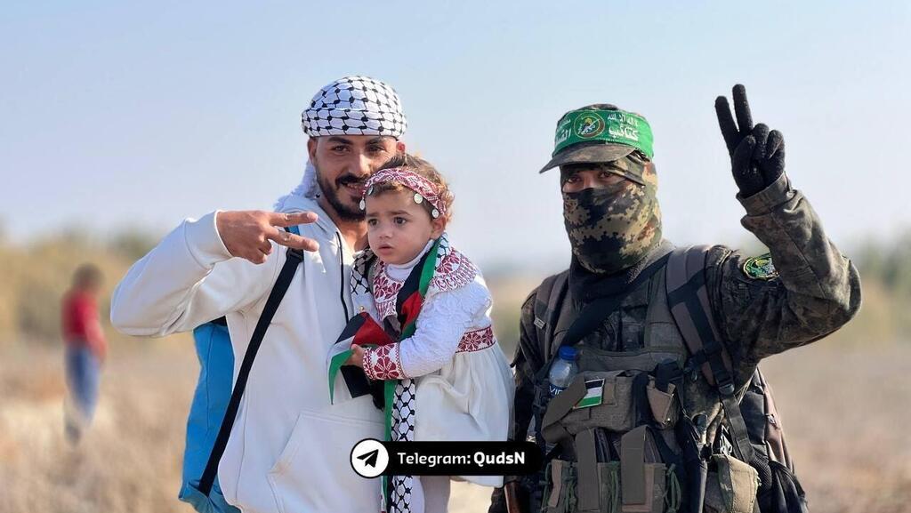 Hamas terrorist greets a father and baby returning to northern Gaza רעולי פנים של חמאס מקבלים את העקורים בצפון רצועת עזה