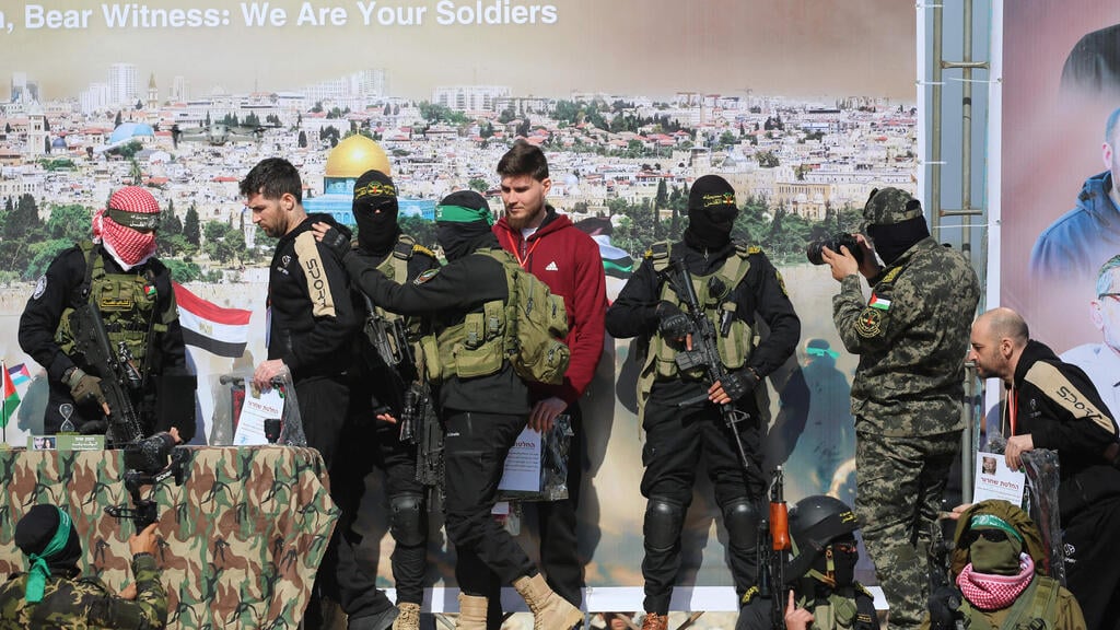 המופע הציני של חמאס (צילום: Eyad BABA / AFP) העברת יאיר הורן, שגיא דקל-חן וסשה טרופנוב לצלב האדום