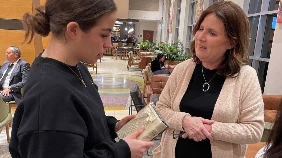 Freed hostage Agam Berger holds a prayer book; she says she prayed to God in captivity (Photo: Shneur Weber) אגם ברגר נפגשה עם צילי שניידר ושניאור ובר