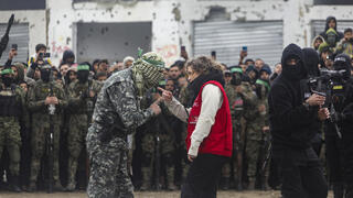 נציגת הצלב האדום מול מחבל חמאס במהלך רגעי שחרור החטופים בפעימה השביעית