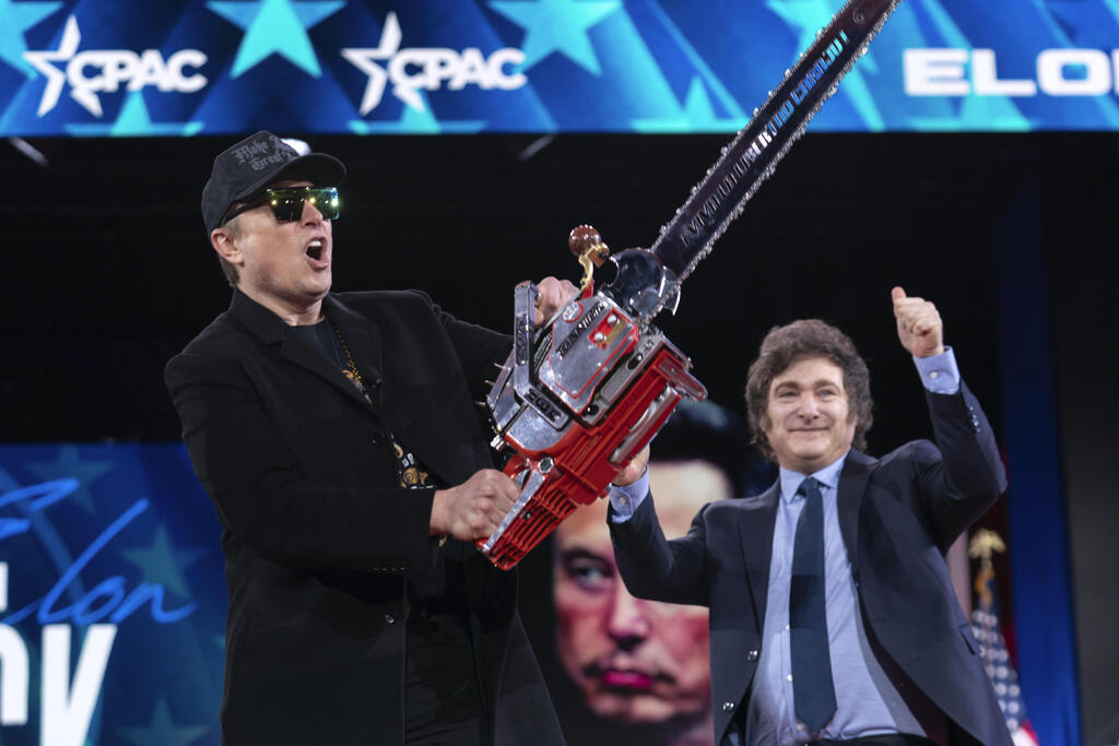 Elon Musk (Photo: AP Photo/Jose Luis Magana) אילון מאסק ב-20 בפברואר ב כנס שמרני ב מרילנד ארה"ב מנופף ב מסור לסימון קיצוצים בממשל