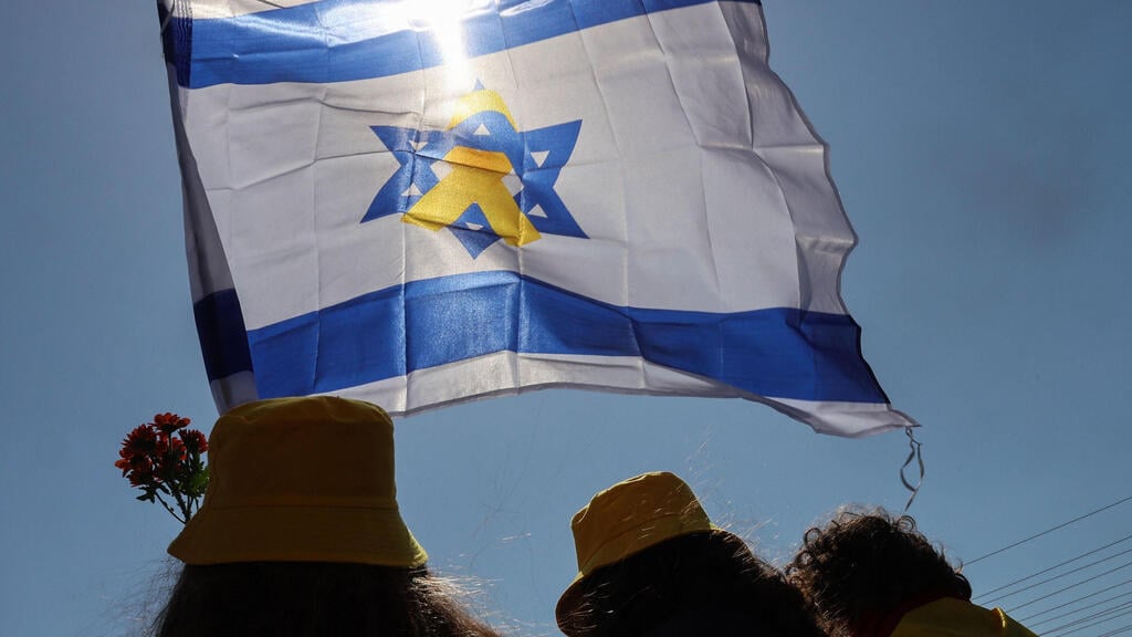 Israeli flag with yellow ribbon (Photo: Jack GUEZ / AFP) דגל ישראל עם סמל החטופים