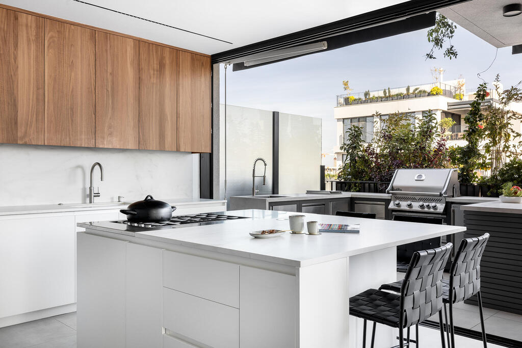 a large square kitchen island in the center (Photo: Oren Amos) דירה לזוג רופאים בגיל הזהב, עיצוב: מיכל אינדיצקי וחגי ויינבלום, Wid Studio