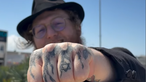 הרב דוד ברסלבסקי מציג את הקעקועים שעל ידו