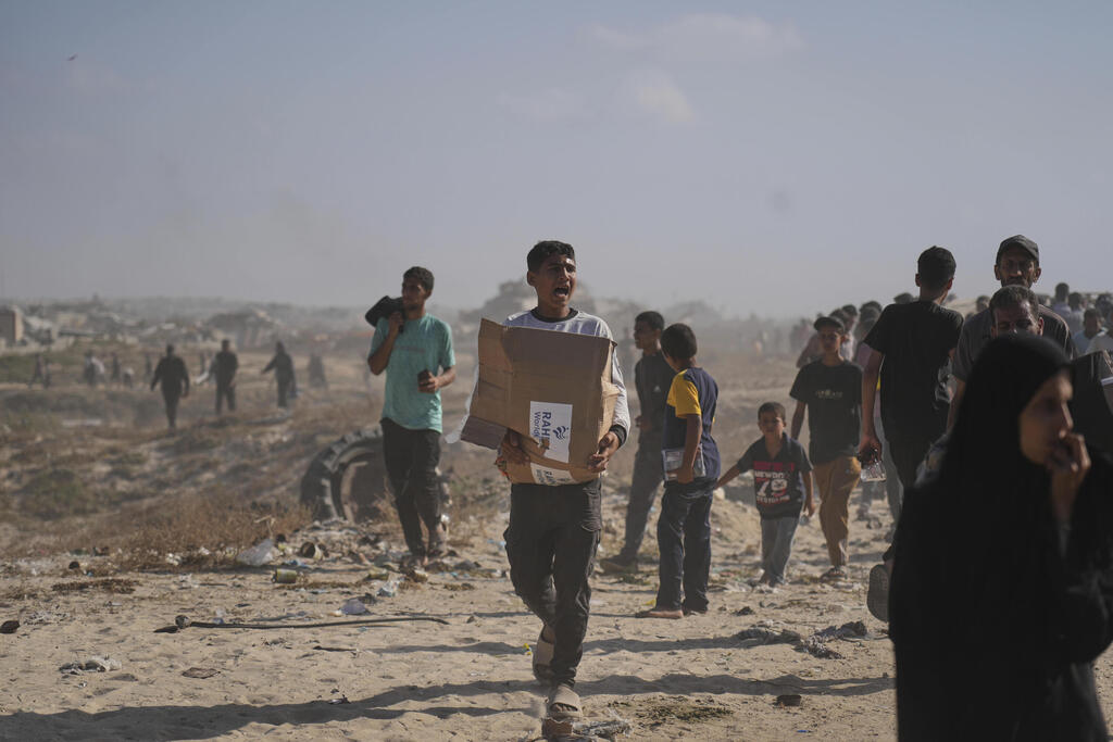 Gazans receive aid in Rafah (Photo: Abdel Kareem Hana/AP) עזתים הולכים לקבל חבילות סיוע המוניטרי ברפיח