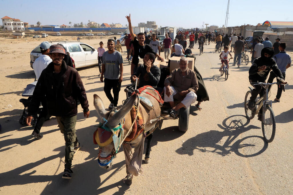 עזתים הולכים לקבל חבילות סיוע המוניטרי ברפיח (צילום: REUTERS/Hatem Khaled) עזתים הולכים לקבל חבילות סיוע המוניטרי ברפיח