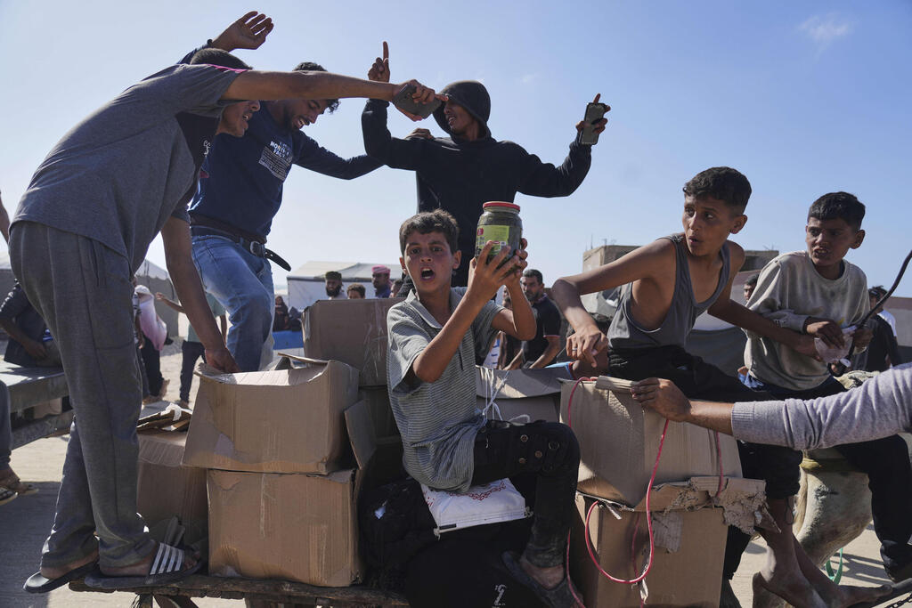 Photo: AP Photo/Abdel Kareem Hana עזתים הולכים לקבל חבילות סיוע המוניטרי ברפיח