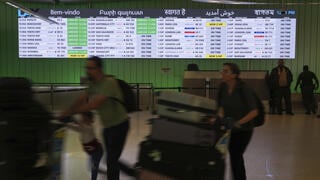 Travelers pass an Arrivals board displays greetings in multiple languages at the Los Angeles International Airport 