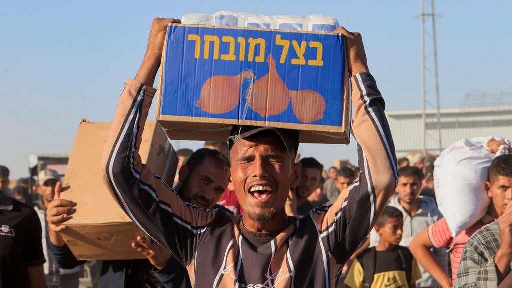 Palestinians collecting aid in Gaza (Photo: REUTERS/Hatem Khaled) פלסטיני סוחב סיוע הומניטרי