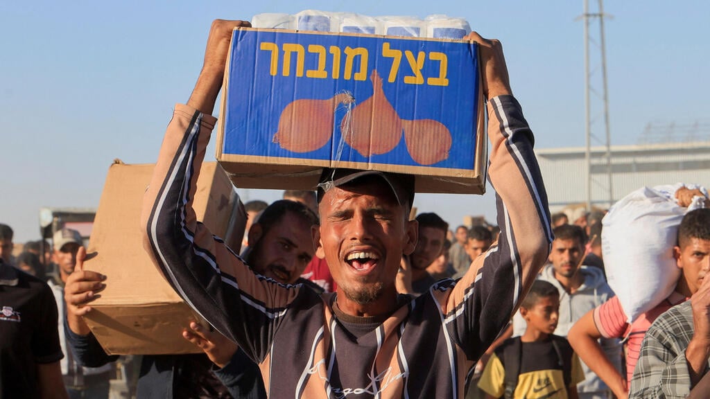 עזתים סוחבים סיוע הומניטרי ברצועה (צילום: REUTERS/Hatem Khaled) פלסטיני סוחב סיוע הומניטרי