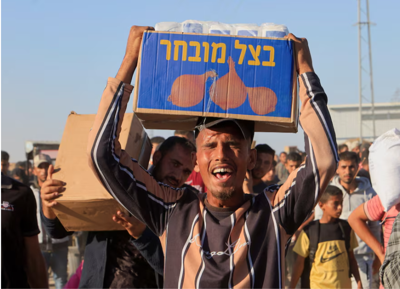 Gaza resident with some of the aid (Photo: REUTERS/Hatem Khaled Purchase Licensing Rights) פלסטיני סוחב סיוע הומניטרי