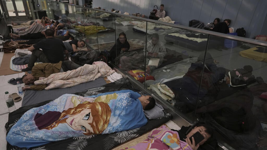 People bed down at the Ramat Gan train station (Photo: Oded Balilty / AP) תופסים מחסה בתינת הרכבת הקלה ברמת גן