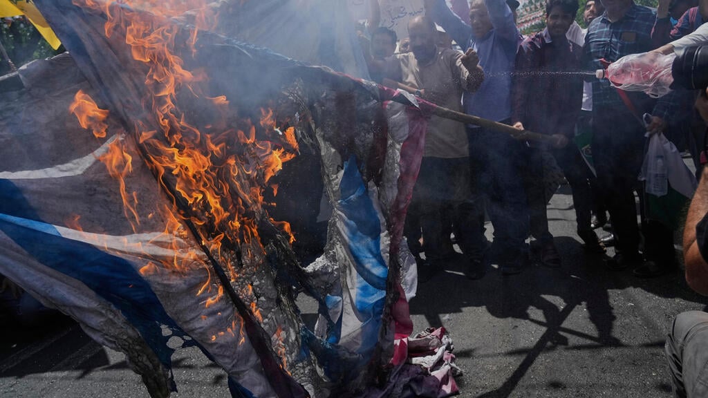 US and Israeli flags burned in Tehran (Photo: Vahid Salemi/AP) הפגנת תמיכה במשטר בטהרן