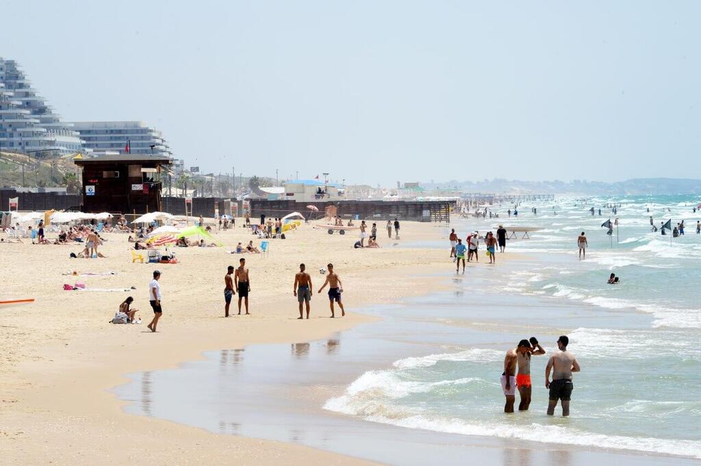 צילום: קובי קואנקס אנשים מבלים בחוף הים במהלך גל חום קיצוני