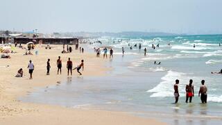 אנשים מבלים בחוף הים במהלך גל חום קיצוני