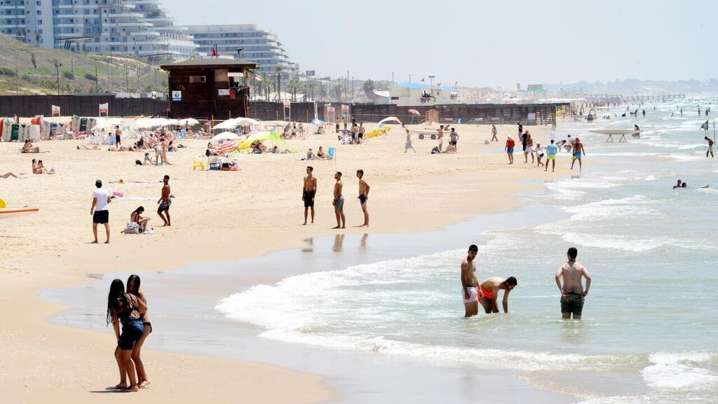 צילום: קובי קואנקס אנשים מבלים בחוף הים במהלך גל חום קיצוני