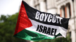 פעילים פרו פלסטינים פרו-פלסטינים מ Palestine Action עם דגל BDS הקורא ל חרם על ישראל בהפגנה מחוץ לבית המשפט ב לונדון נגד הכרזה על הארגון כארגון טרור בריטניה 