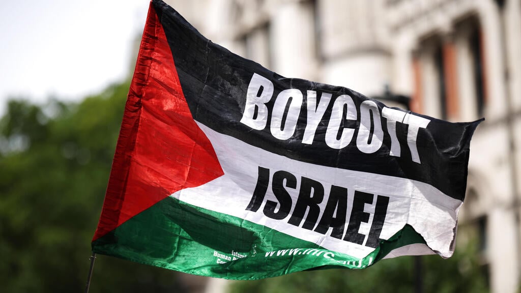 פעילים פרו פלסטינים פרו-פלסטינים מ Palestine Action עם דגל BDS הקורא ל חרם על ישראל בהפגנה מחוץ לבית המשפט ב לונדון נגד הכרזה על הארגון כארגון טרור בריטניה 