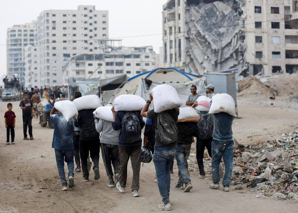 פלסטינים נושאים שקי סיוע ברצועה (צילום: REUTERS/Khamis Al-Rifi) עזה