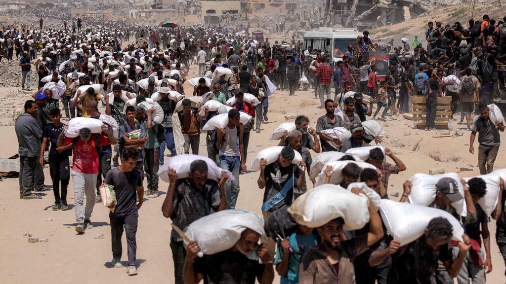 תושבי הרצועה נושאים שקי סיוע (צילום: BASHAR TALEB / AFP, BASHAR TALEB / AFP) חלוקת סיוע הומניטרי ברצועת עזה