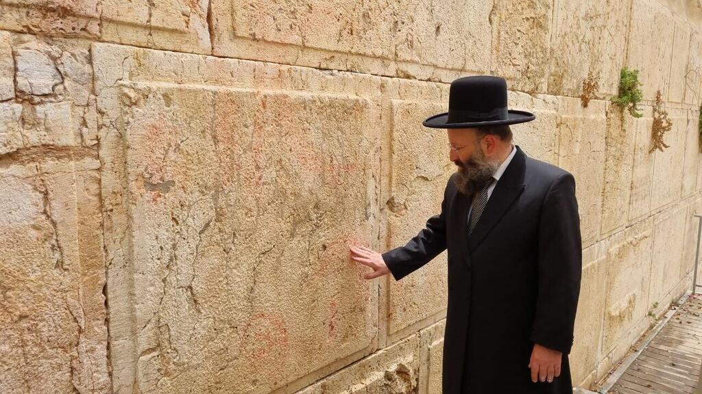 הרב שמואל רבינוביץ במקום שבו נמצאה הכתובת, לאחר הניקוי (צילום: הקרן למורשת הכותל המערבי) הרב שמואל רבינוביץ במקום שבו נמצאה הכתובת, לאחר הניקוי