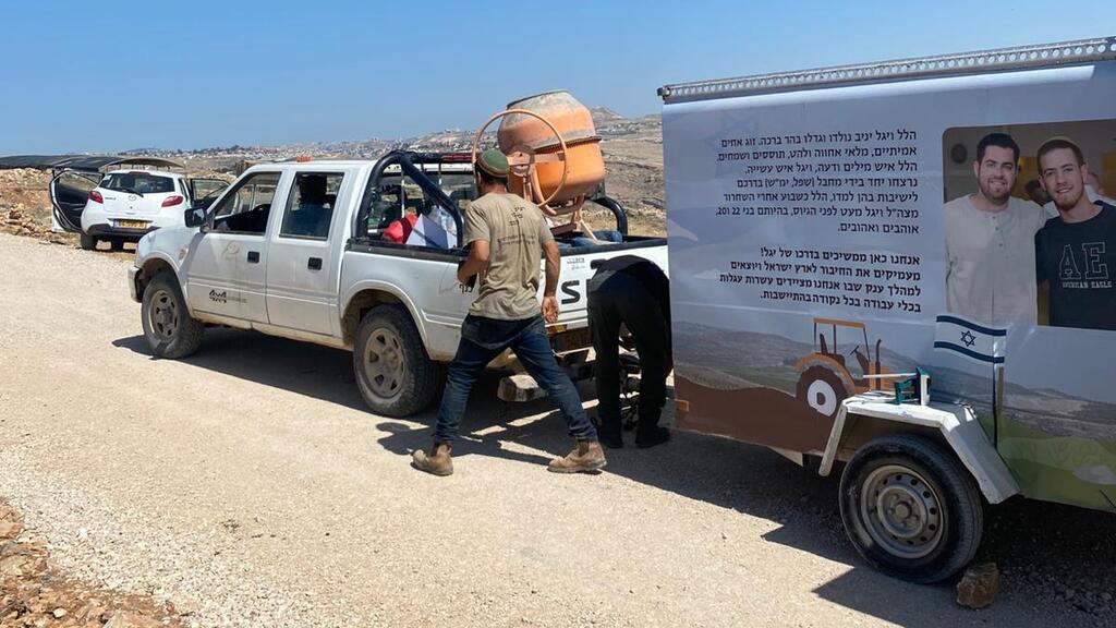A man attaches a trailer carrying farming and construction equipment to a vehicle as part of the new Carts of Strength initiative, launched by Israeli military veterans to support agricultural outposts and honor fallen soldiers 
