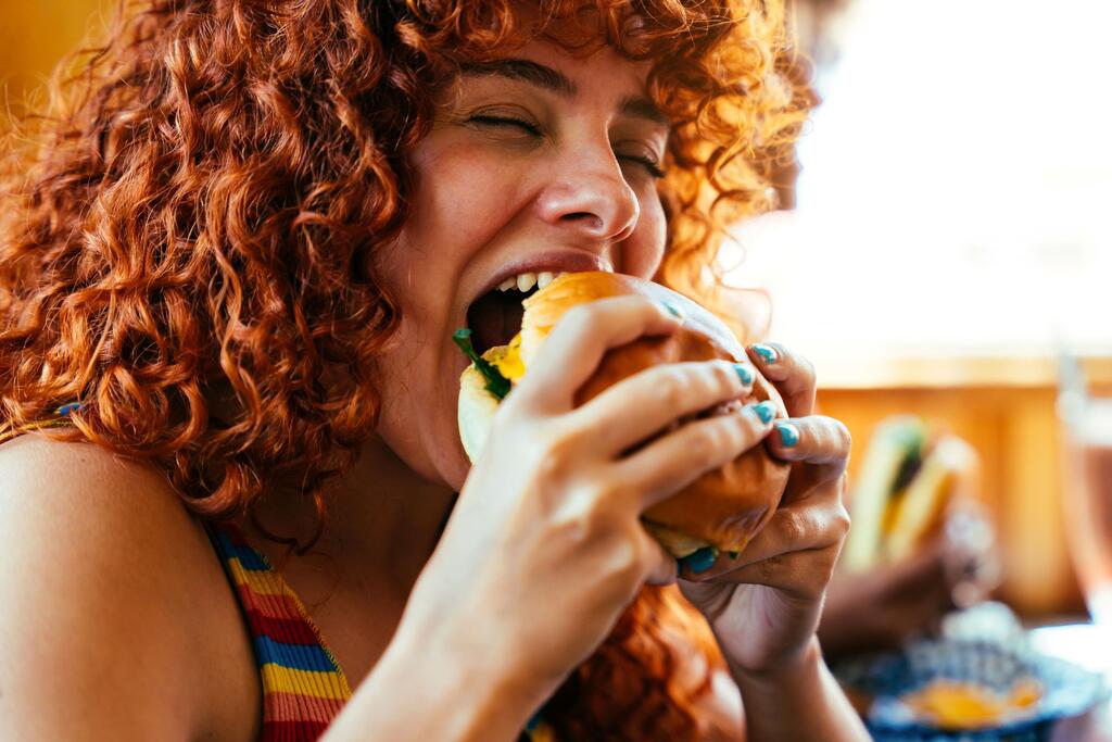 Photo: Shutterstock אישה אוכלת המבורגר