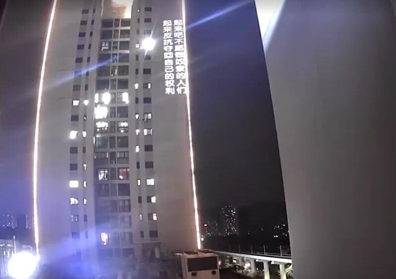 כתובת מחאה של צ'י מוקרנת על המגדל הסמוך, בתיעוד שהופץ ברשת מחאה נגד המפלגה הקומוניסטית על בניין ב סין הקרין וברח