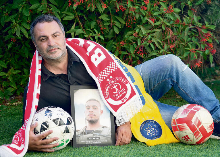 יניב אליהו עם תמונת בנו יאיר ז"ל. גם צהוב, גם אדום | צילום: תומר שונם הלוי yk14515143