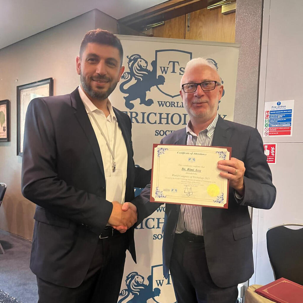 ד"ר רימי עאסי לצד ד"ר דוד קינגסלי, ראש הארגון העולמי לטריכולוגיה (WTS) במעמד קבלת המינוי כדירקטור האזורי של הארגון במזרח התיכון