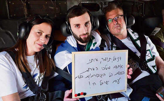 מתן במסוק עם הוריו. על השלט שמות חבריו שנפלו בקרב | צילומים: דובר צה"ל yk14545341