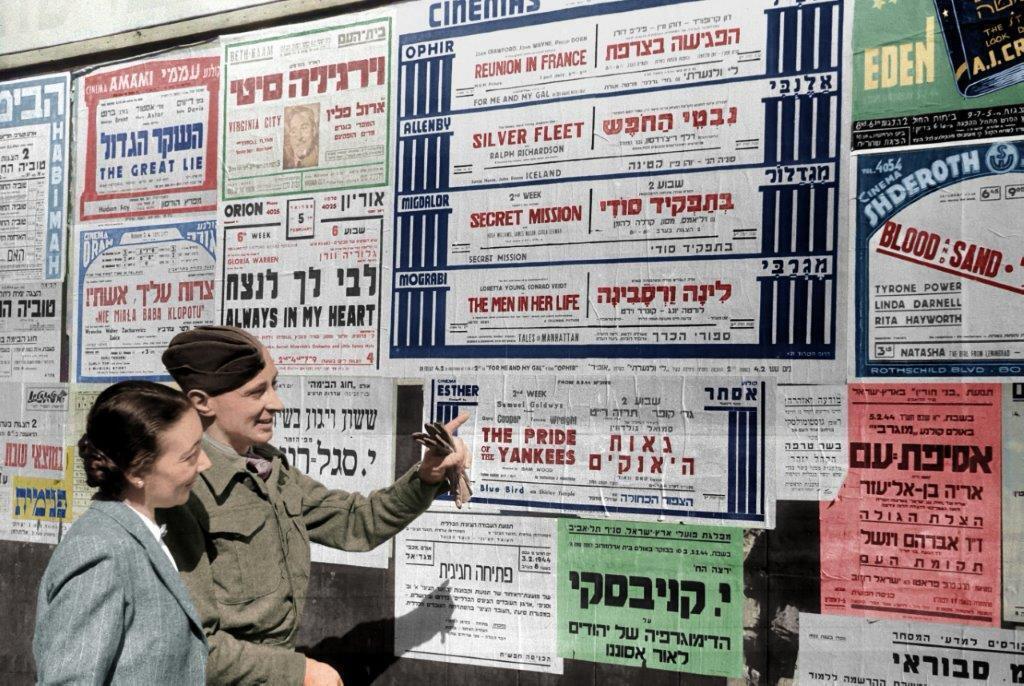 לוח מודעות תל אביבי, 1942 (צילום: לזר דינר, ארכיון הצילומים של קק"ל. צביעה: תמר הירדני) ליד לוח מודעות עירוני