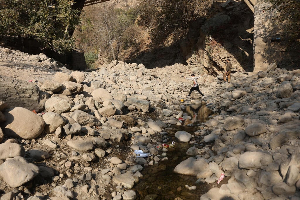 A man jumps across a nearly dry riverbed in the Kan River in Tehran, Iran, as the country faces a severe water crisis (Photo: Majid Asgaripour/WANA (West Asia News Agency) via REUTERS) נהר קאן ב טהרן איראן משבר מים בצורת