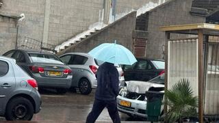 אור עקיבא: תושב המקום בגשם הסוער עם מטרייה וכפכפים - סופת ביירון