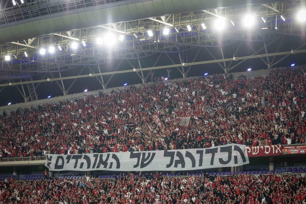 אוהדי הפועל ת"א עם שלט המחאה "הכדורגל של האוהדים" (צילום: עוז מועלם) עירוני קריית שמונה - הפועל ת"א