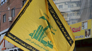 A man holds a Hezbollah flag, ahead of Pope Leo XIV's arrival in Lebanon during his first apostolic journey, at Haret Hreik, the southern suburbs of Beirut, Lebanon, November 30, 2025