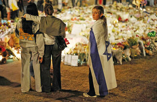 זוכרים את הקורבנות והגיבורים. צעירה עם דגל ישראל באתר הזיכרון המאולתר בסידני