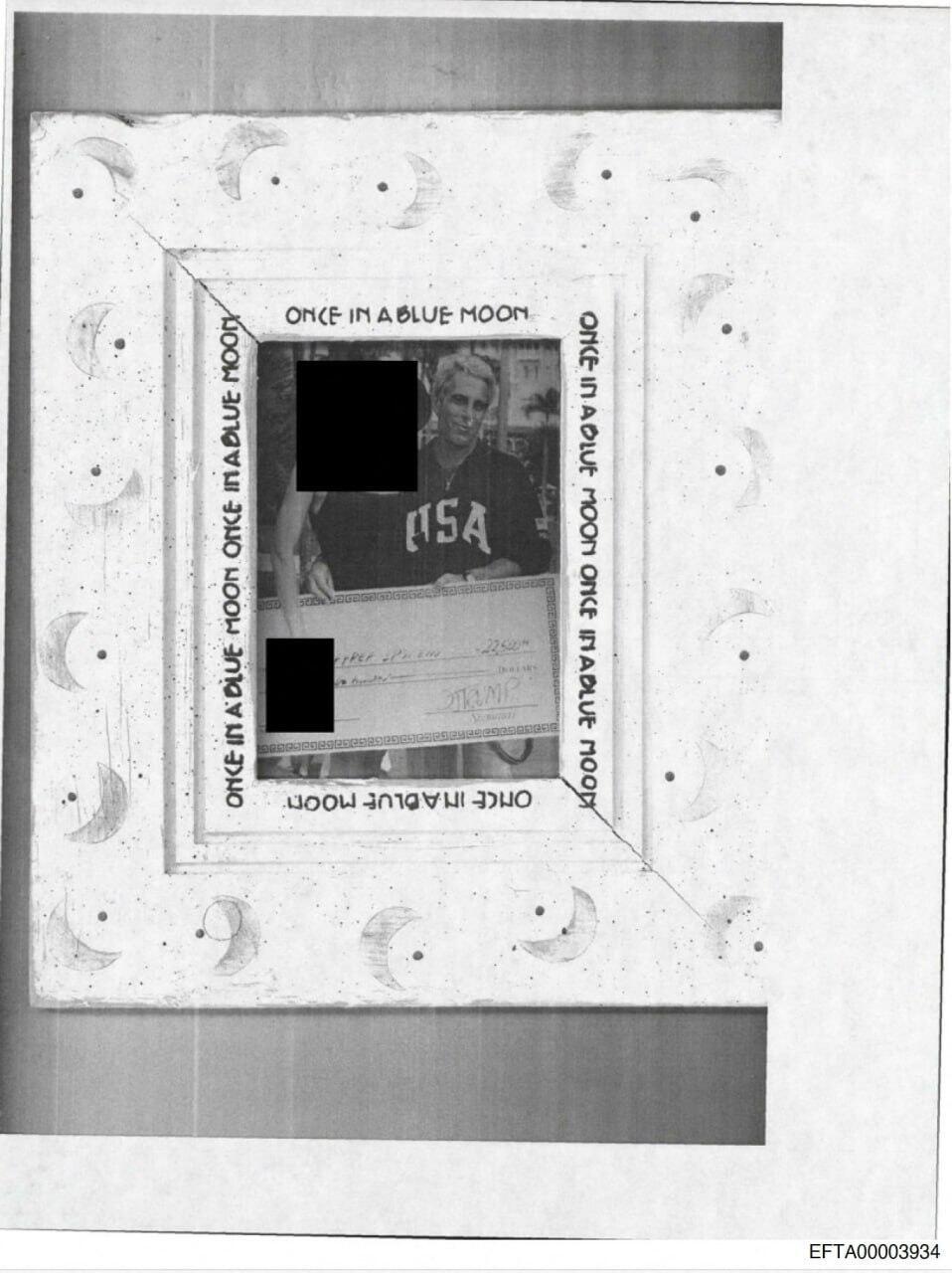 A framed photograph featuring Jeffrey Epstein holding a large check. Other individuals in the image have been redacted. Trump's name appears on the check (Photo: Reuters) תמונה של ג'פרי אפשטיין, המחאה עליו מופיעה שמו של טראמפ