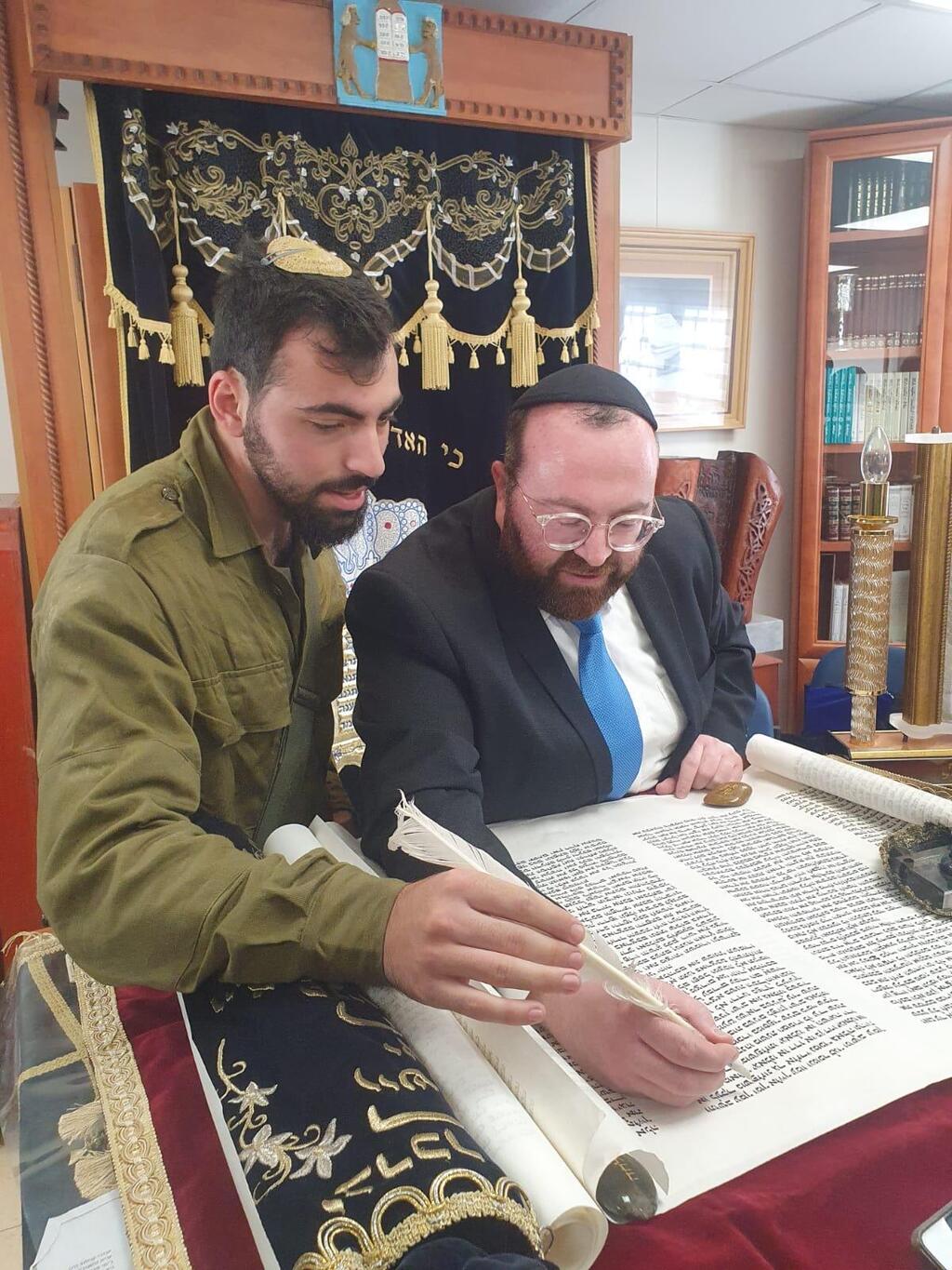 Amichai Oster writes a letter in a new Torah scroll dedicated at Kibbutz Be'eri just weeks after the start of the war (Photo: Courtesy) Amichai Oster writes a letter in a new Torah scroll dedicated at Kibbutz Be'eri just weeks after the start of the war