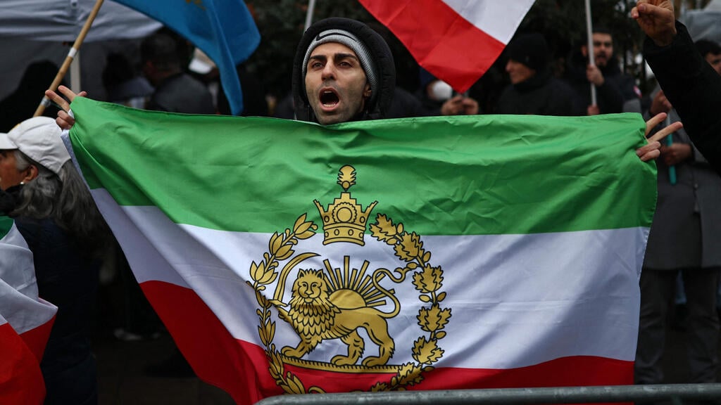 Pro-Iranian protest in London, with Iran’s former flag associated with the Persian shah (Photo: Henry NICHOLLS / AFP) דגל השאה הקודם של איראן עם סמל האריה והשמש ב הפגנה לונדון 9 בינואר