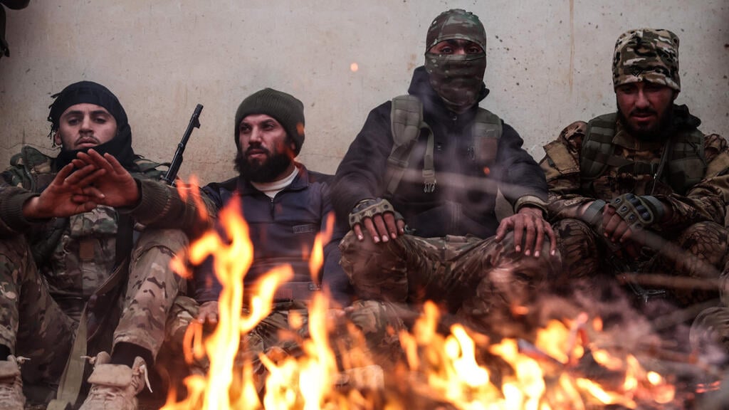 Al-Sharaa fighters warm themselves around a campfire in the al-Tabqa area, in the al-Raqqa province (Photo: Omar Haj Kadour / AFP) כוחות משטר א-שרע צבא סוריה אזור א-טבקה במחוז דיר א-רקה 17 בינואר