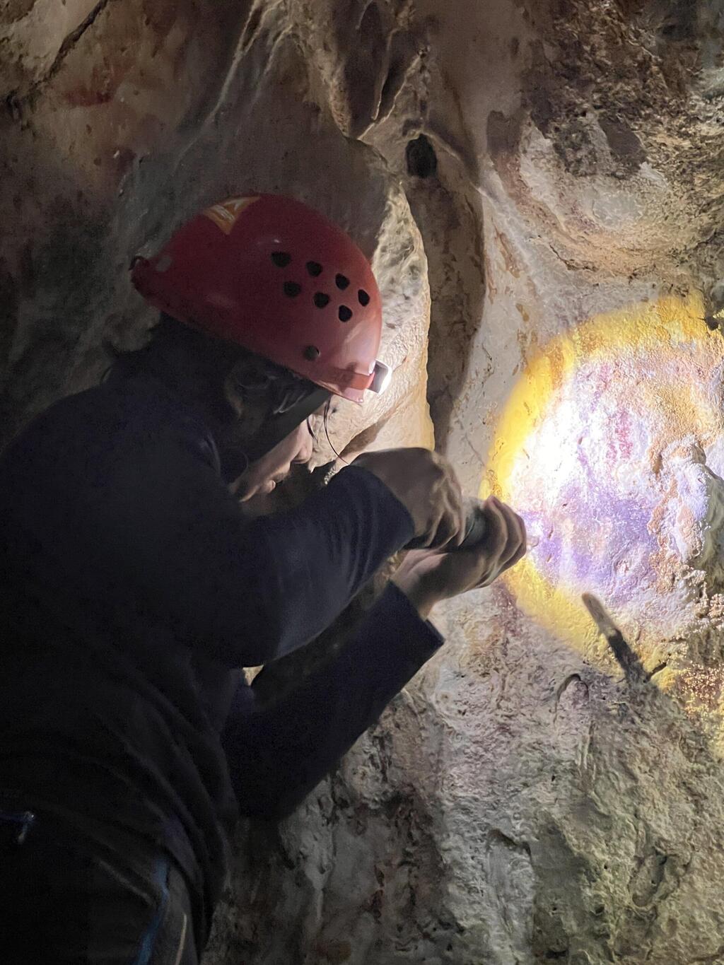 ד"ר אדהי אגוס אוקטביאנה מאיר על אמנות סלע בצורת כף יד, שנמצאה באי סולאווסי (צילום: Max Aubert) ד"ר אדהי אגוס אוקטביאנה מאיר על אמנות סלע בצורת כף יד, שנמצאה באי סולאווסי