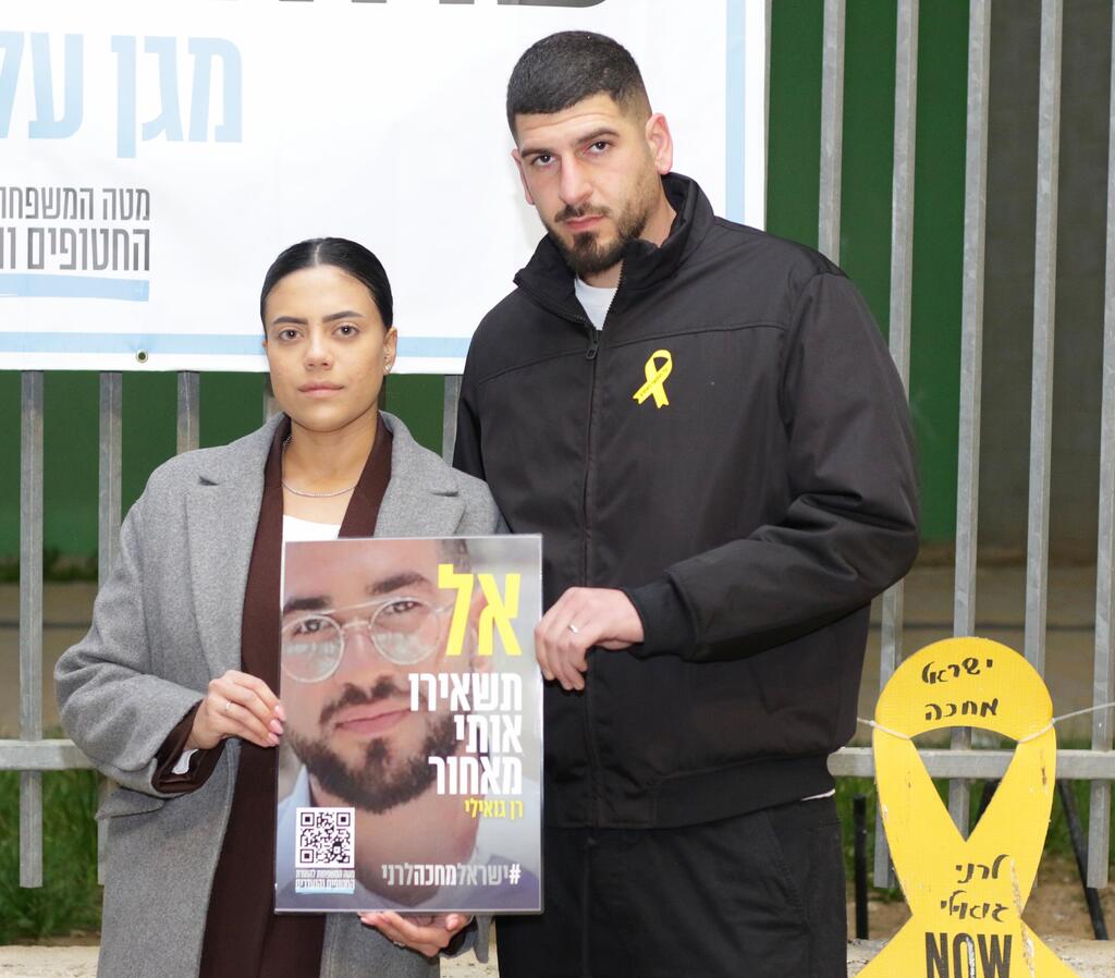 עומרי, אחיו של רן, עם אשתו שרון והתמונה של רן: "אל תשאירו אותי מאחור" (צילום: מאיר אבן חיים) עצרת מיתר בקריאה להשבתו של רן גואילי ז"ל