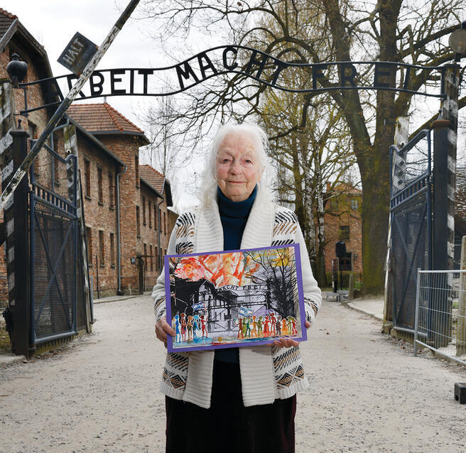 חנה יכין בכניסה למחנה אושוויץ, עם הציור שיצרה לקראת מצעד החיים. אתמול