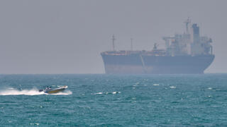 סירה קטנה שטה ליד מכלית ספינה סמוך לאי האיראני קשם  מצר הורמוז שנחסם על ידי איראן