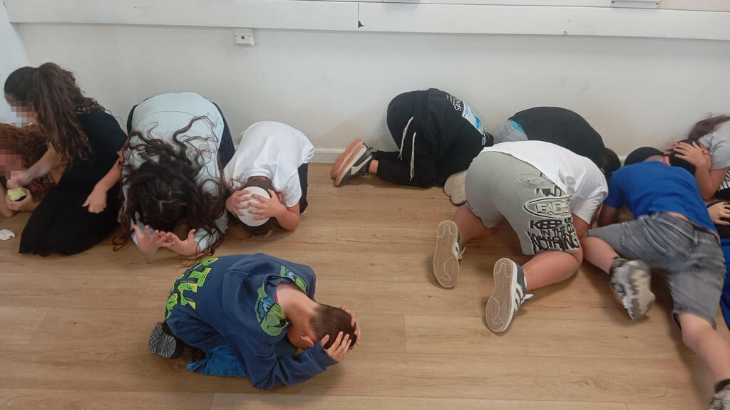 בפינת הכיתה, עם ידיים על הראש. כך מתמגנים תלמידים בשלומי בזמן אזעקות תלמידים מתגמנים בבית ספר בשלומי