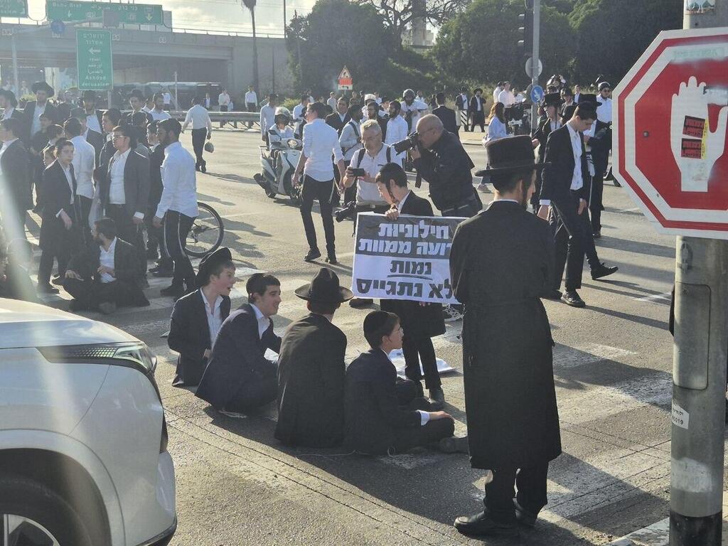 על השלטים: "חילוניות גרועה ממוות" (צילום: מוטי קמחי ) הפגנת חרדים בכביש 4
