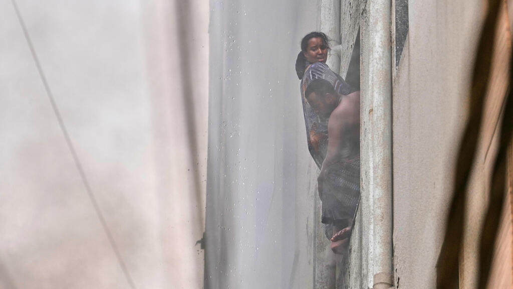 לכודים קופצים מהחלון (צילום: AP Photo/Manish Swarup) לפחות 21 נספו בשריפה במלון בניו דלהי, הודו